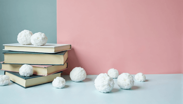 Books laying on top of each other, surrounded by snowballs